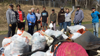 A group of volunteers standing behind bags of trash collected frrom a nearby creek during the Big Spring Clean.